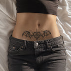 Woman wearing the Nightwing Crest succubus temporary tattoo above low-rise black jeans