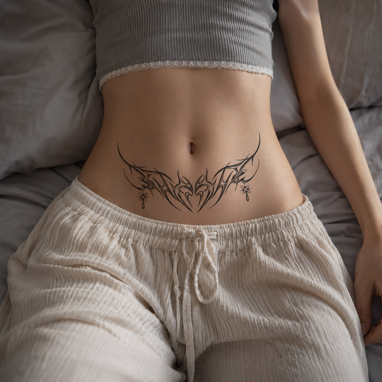Woman wearing the Starlit Thorn black tribal temporary tattoo on the lower stomach