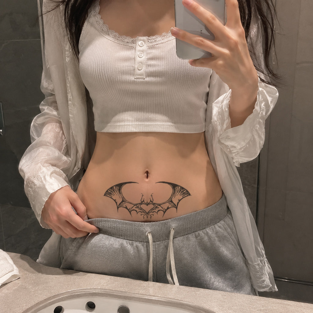 bat wing heart temporary tattoo applied above the lower stomach in black gothic style